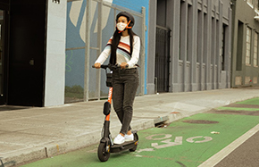 A woman riding a Spin escooter through a downtown area