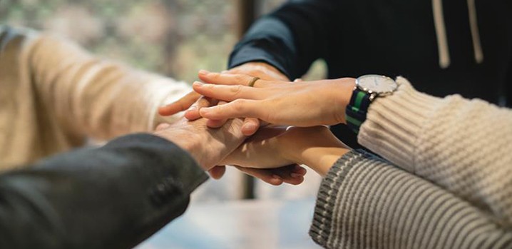 four people putting hands in