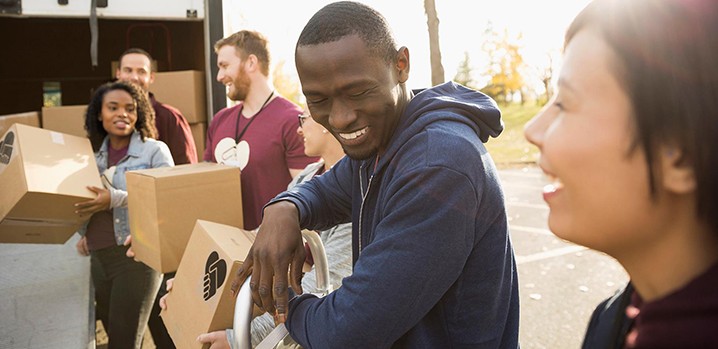 group of colleagues laughing and carrying boxes outside