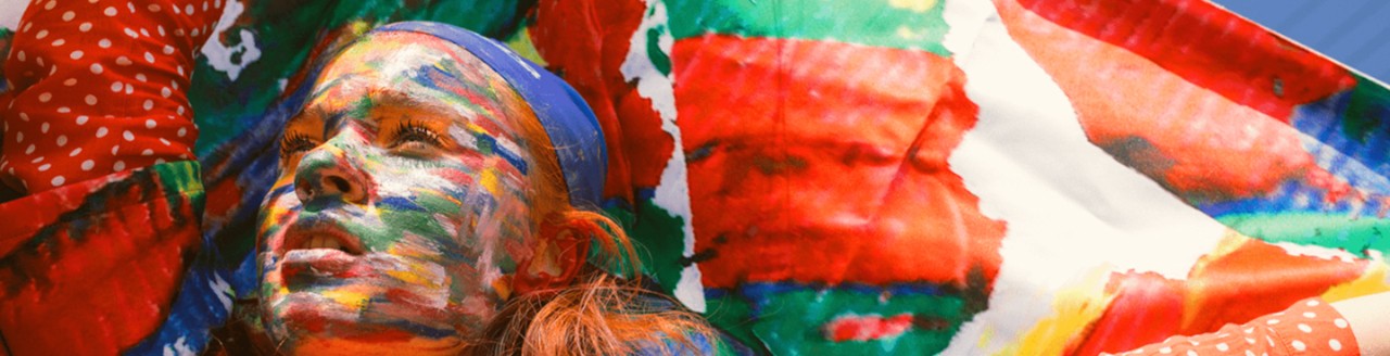 Girl with colorfully painted face over flag wearing polkadots