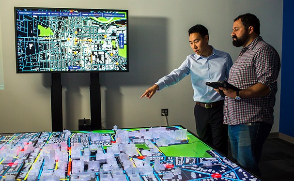 Two men looking and monitor and scale model of city