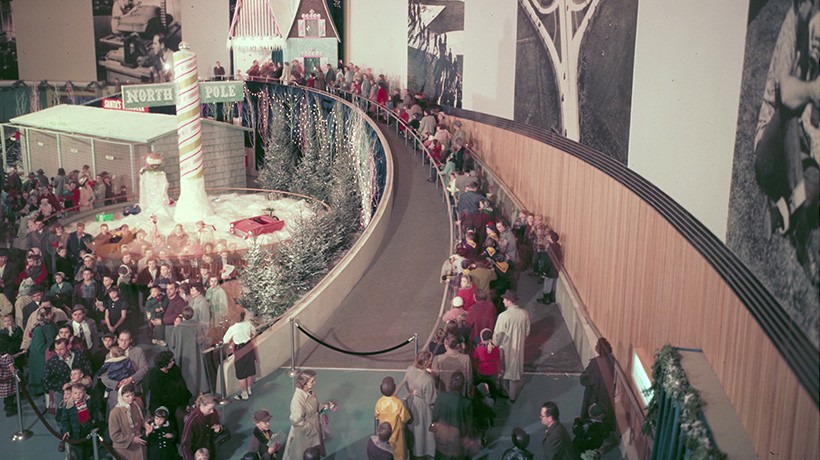 A large group of people standing in line inside a building with Christmas decorations