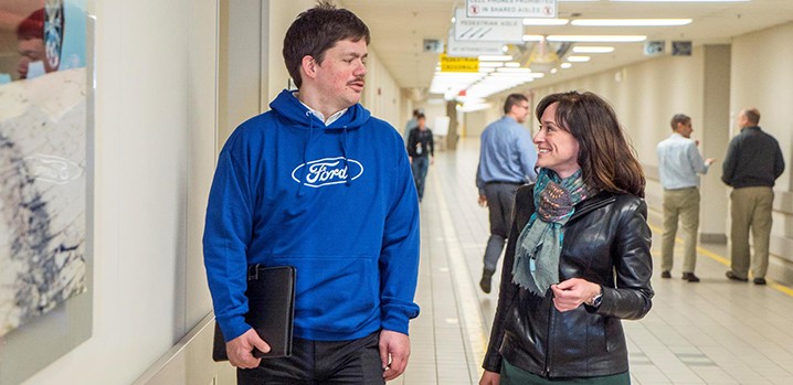 Man in blue Ford sweatshirt talking to woman in hall