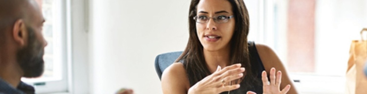 Image a man and woman talking in a conference room