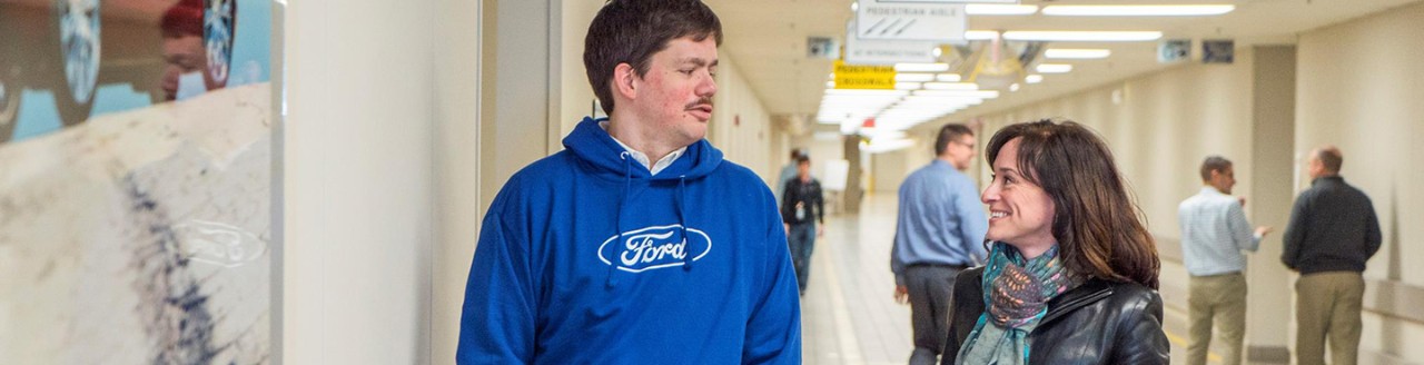 Man in blue Ford sweatshirt talking to woman in hall