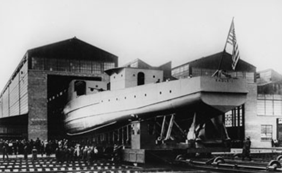 A black and white image of a patrol boat coming out of a factory