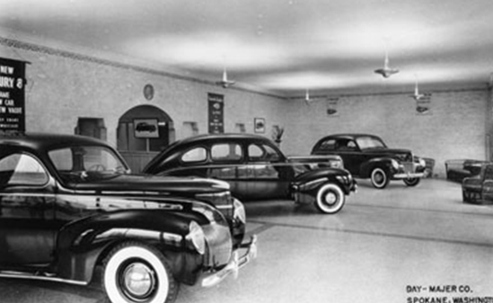 A black and white photo of a car dealership showroom