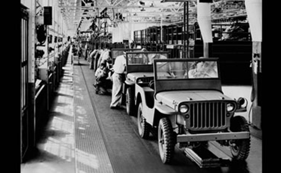Black and white photo of Jeeps on an assembly line