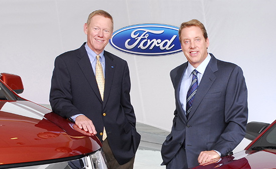 Color photo of two men standing by a car