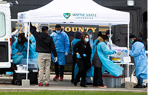 van and tent with badging and people getting tested for covid