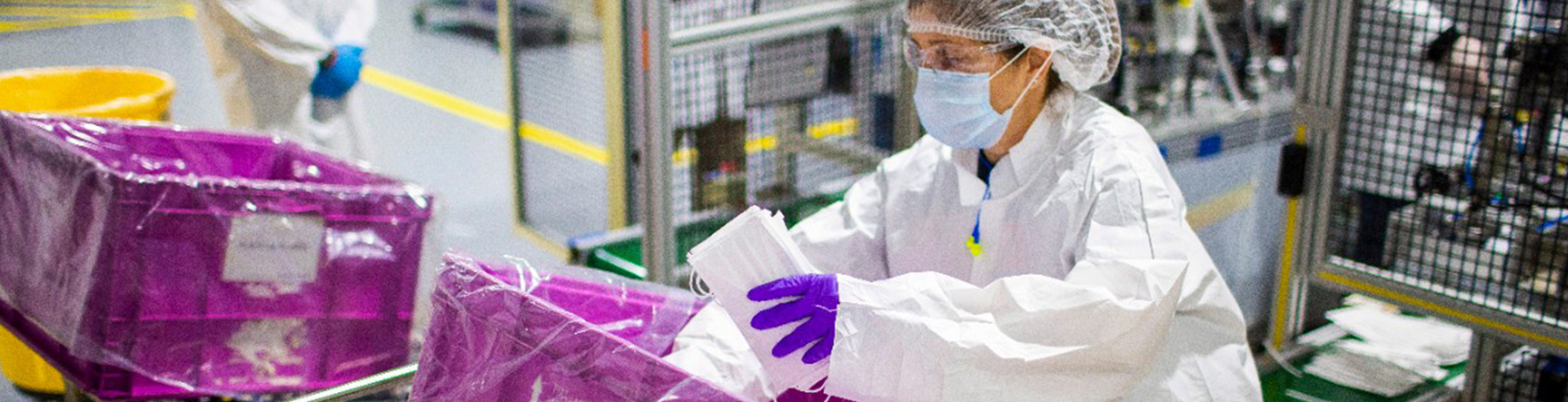 A woman placing face masks into a large pink bin