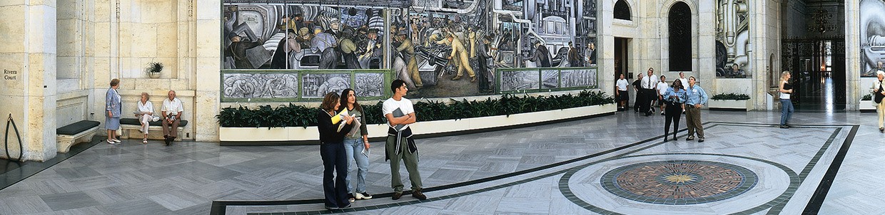 Many small groups of people observing art in a museum