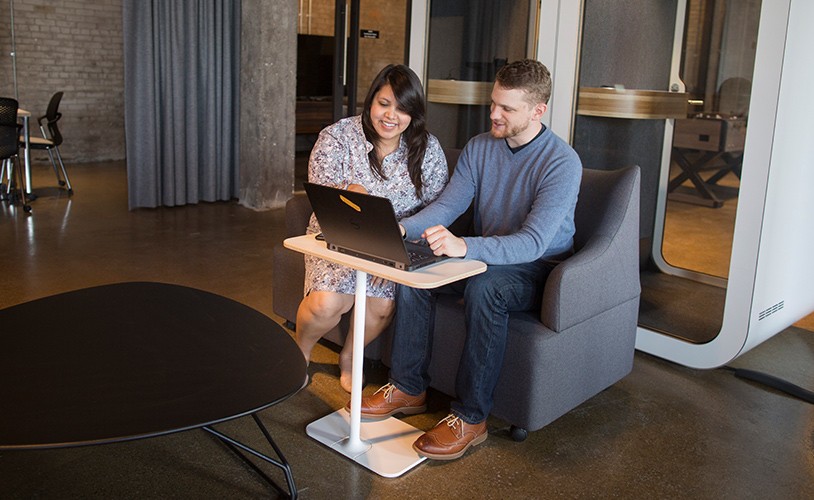 A female Ford employee and male Ford employee sitting together and looking at a laptop smiling