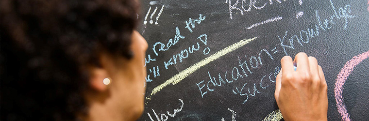 A person writing on a chalk board. Ford Rocks! Education=Knowledge...
