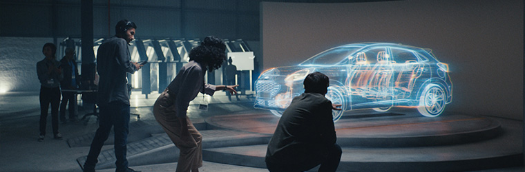 Three people looking and pointing at a car hologram