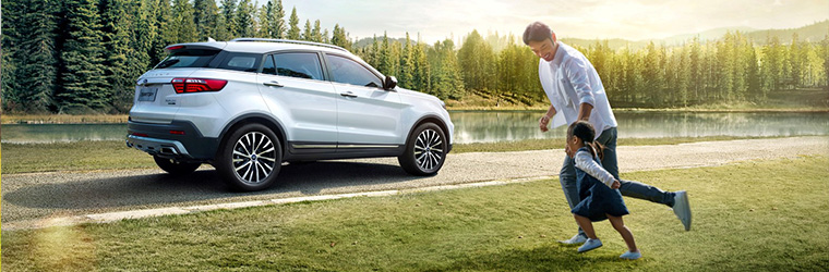 A man and child moving towards their car with a forest and river in the background