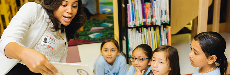 A woman reading a book to four children
