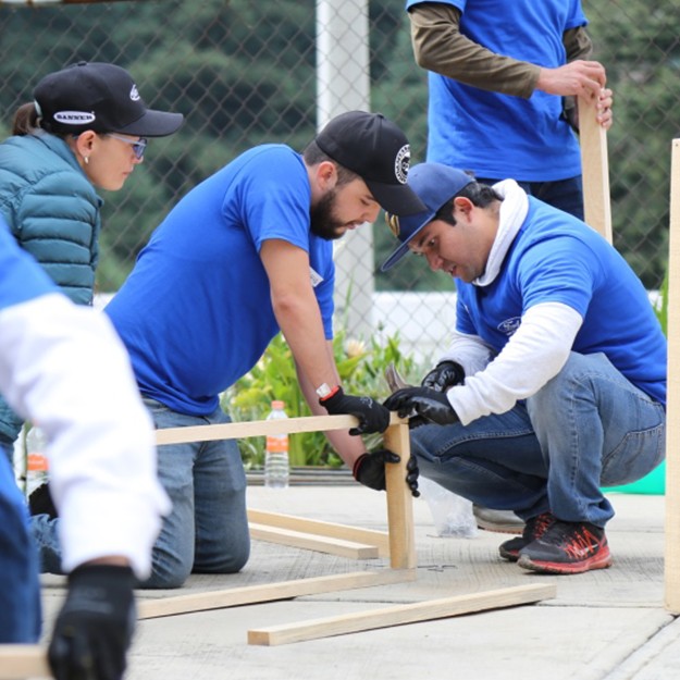 A few people holding wood to hammer together