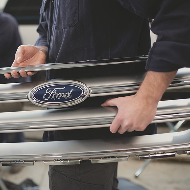 Ford employee holding a part of a car