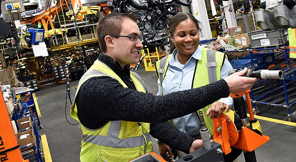 Two people in high-visibility jackets inside of a warehouse