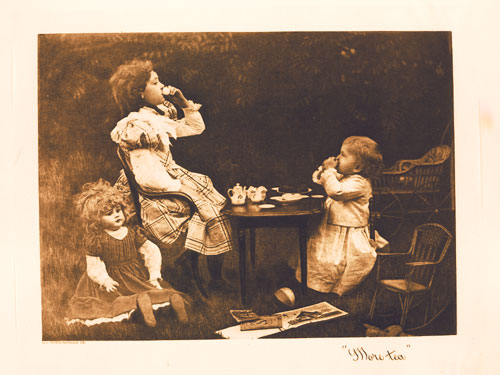 Image of two children and a doll at an outdoor tea party.