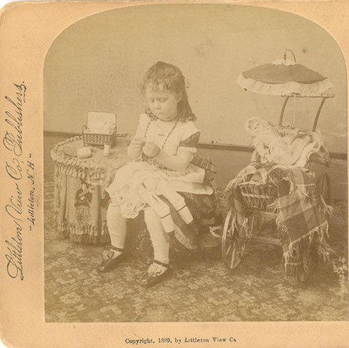 Image of a girl sewing and playing with dolls.