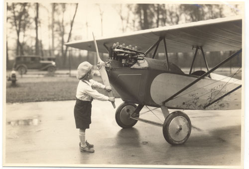 Image of a boy turning the propeller of a model airplane.