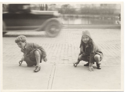 Image of two children playing outdoors with model cars.